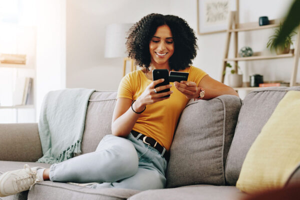 Credit-card,-happy-and-woman-on-sofa-with-phone-for-online-shopping,-web-store-sale-and-purchase.
