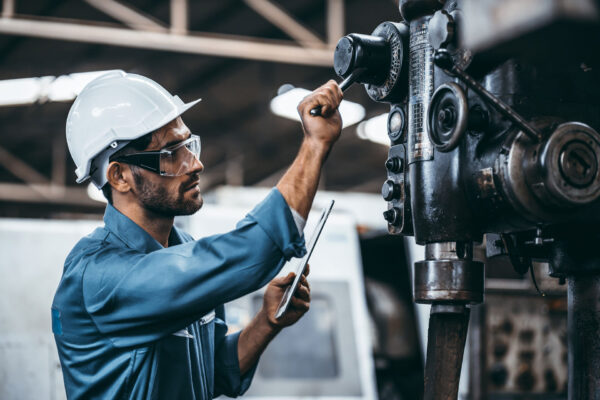 Engineer-working-at-industrial-machinery-in-factory.-Manual-workers-cooperating-while-measuring-a-electronic.