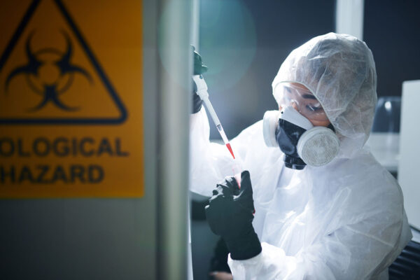 Gefahrenstoffe----Concentrated-laboratory-scientist-in-protective-workwear,-rubber-gloves,-goggles-and-respirator-complying-with-safety-while-working-with-infected-substance