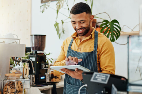 Mann – Barista im Handel mit SAP Customer Checkout fuer SAP Business One Waiter, smile and tablet in coffee shop for business, online order and delivery service platform. Male barista, tech and software in restaurant for POS, stock management or company information update