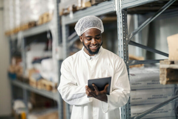 Storage-manager-in-sterile-uniform-working-on-checklist-and-smiling-at-tablet-at-warehouse Storage-manager-in-sterile-uniform-working-on-checklist-and-smiling-at-tablet-at-warehouse