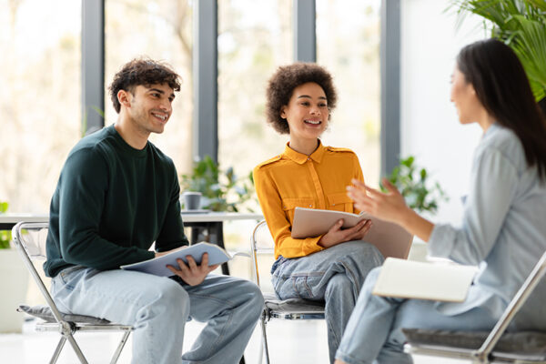 College collaboration. Cheerful multiracial students talking and discussing their educational project together, sitting in classroom on chairs