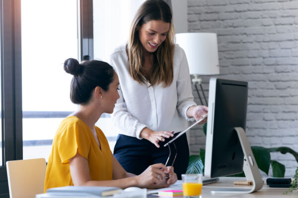 Two-young-businesswomen-reviewing-work-via-digital-tablet-in-the-office.